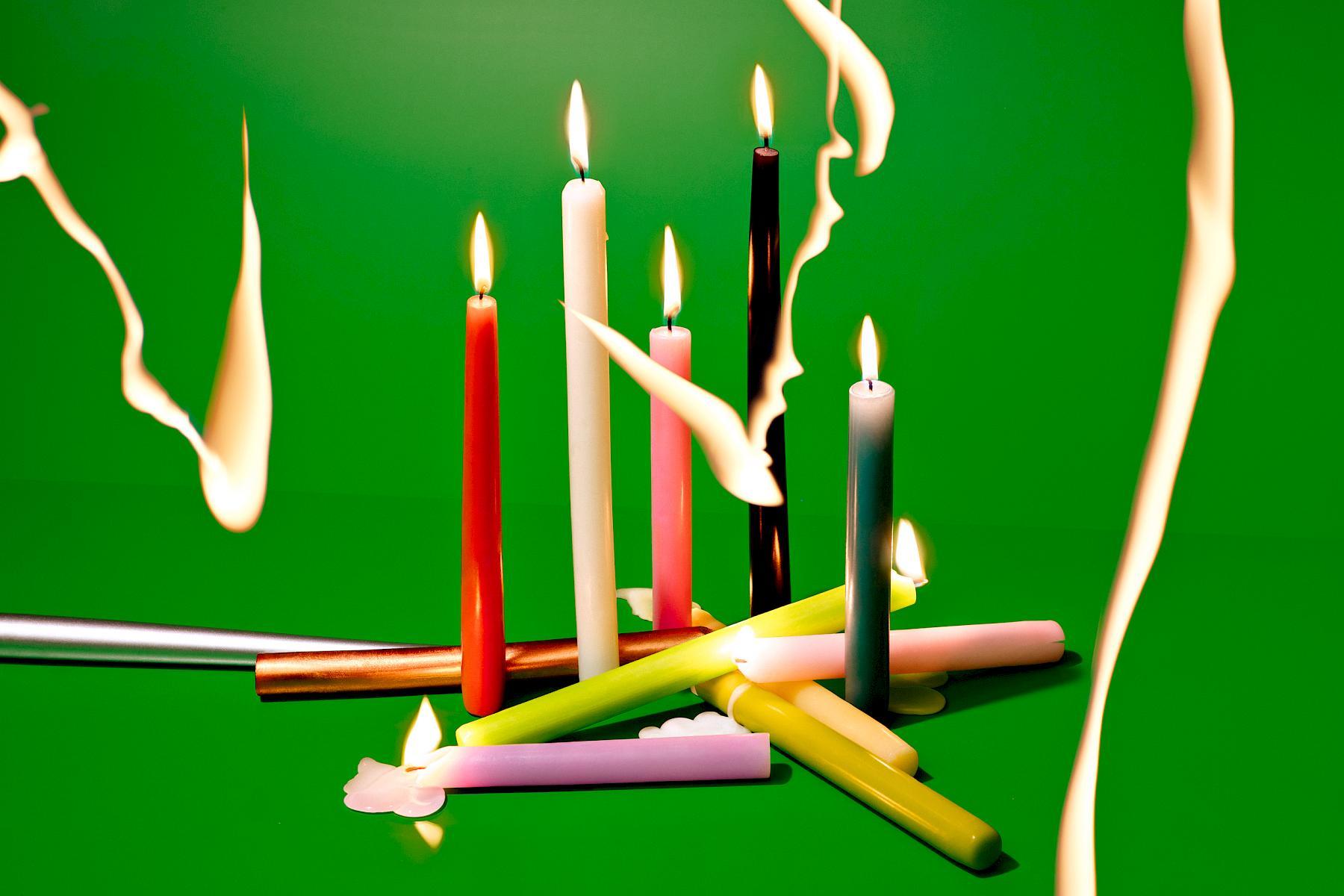 Colourful candles on a green background with light drawing