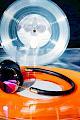 Frends taylor oil slick wired headphones lying on a bright orange vinyl record