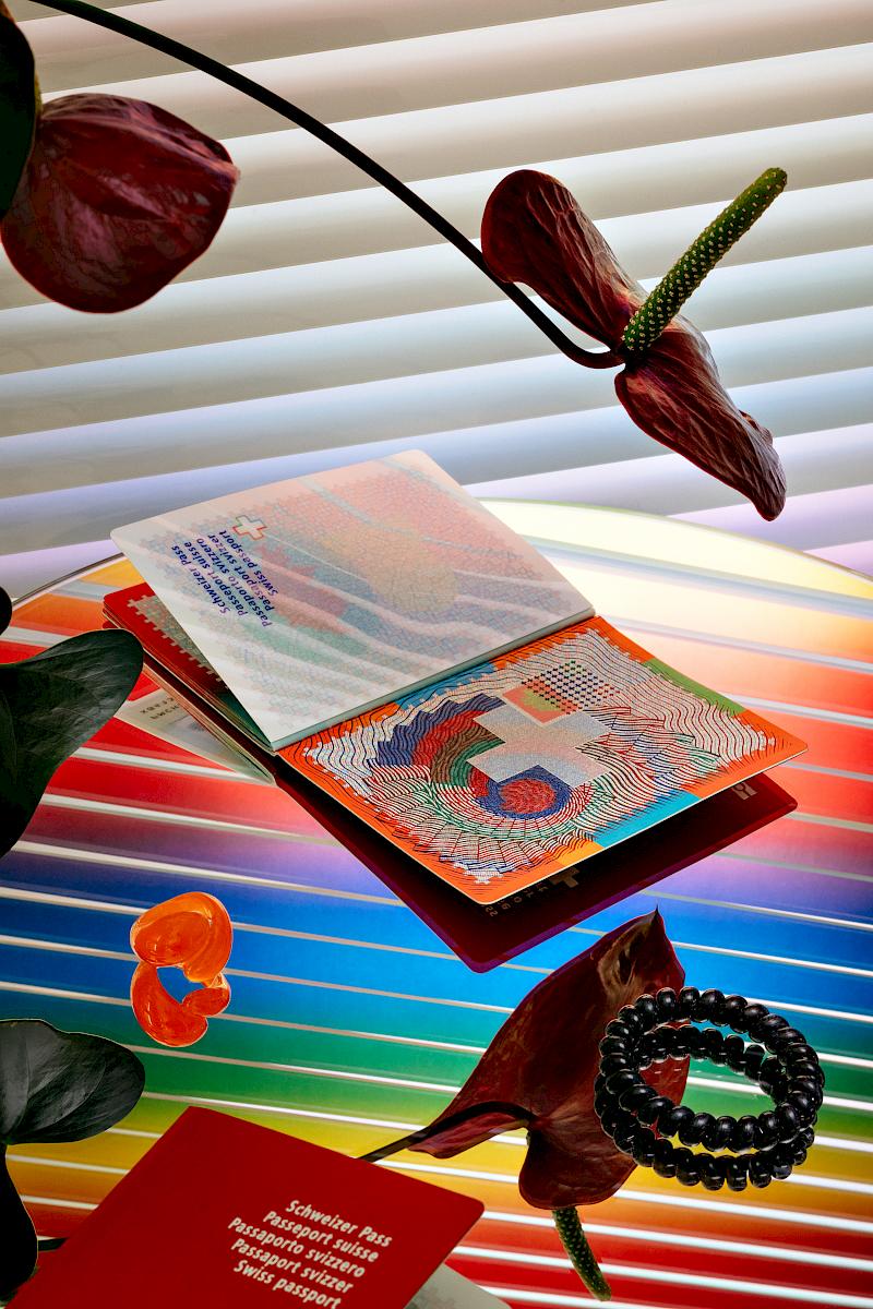 Contemporary Swiss biometric passport from 2010 on a rainbow reflection with flamingo flowers, a bracelet and a ring