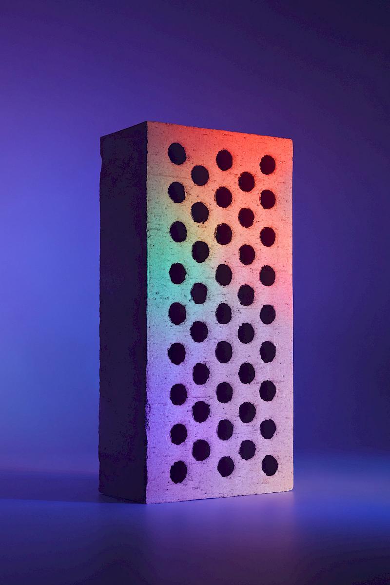 A brick on a blue background illuminated with colourful lights