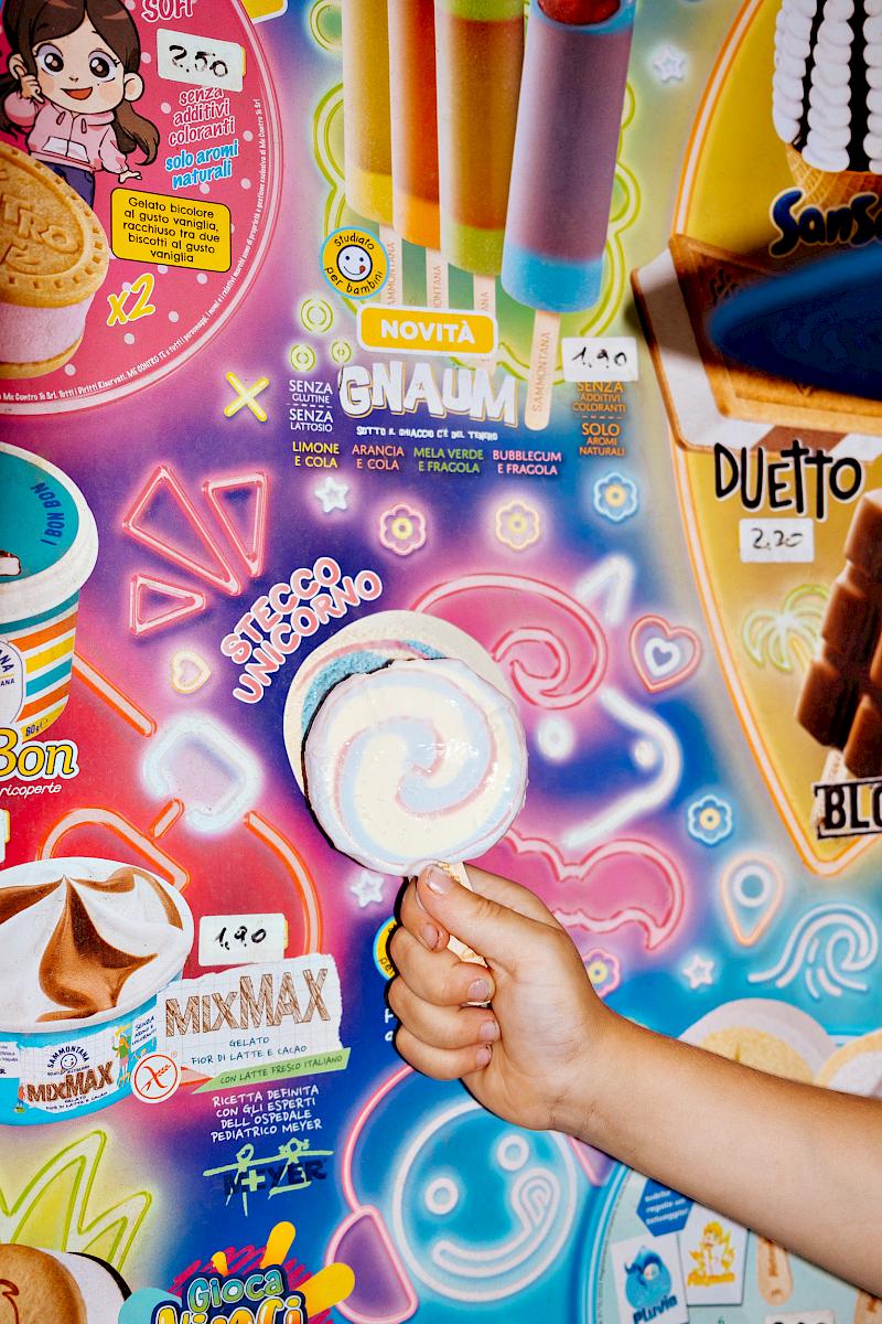 Child's hand holding an ice cream in front of an ice cream menu