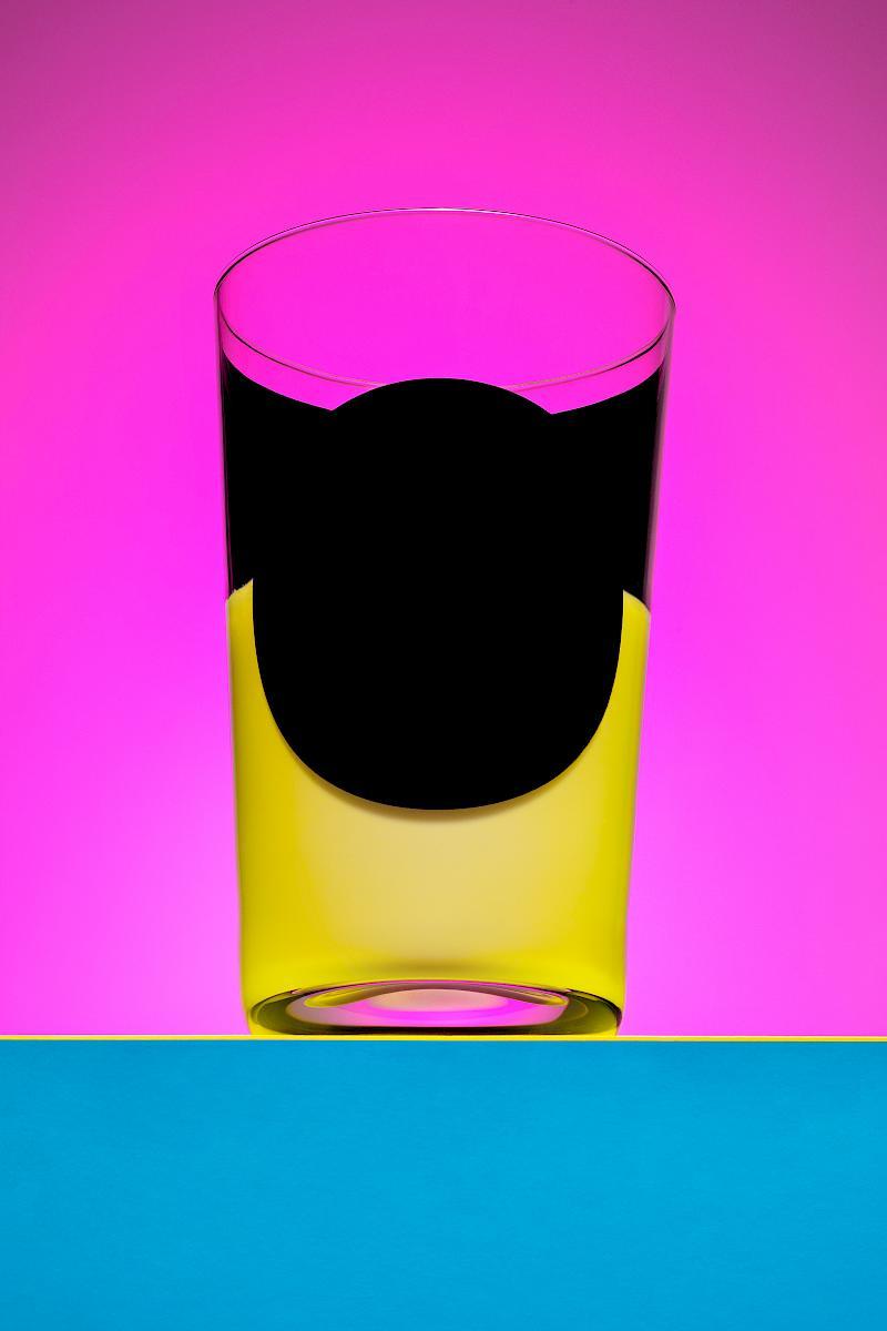 A glass of milk photographed in front of a pink background on yellow paper