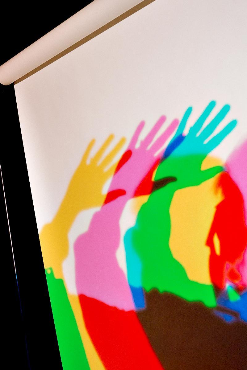 Three coloured shadows of an arm waving